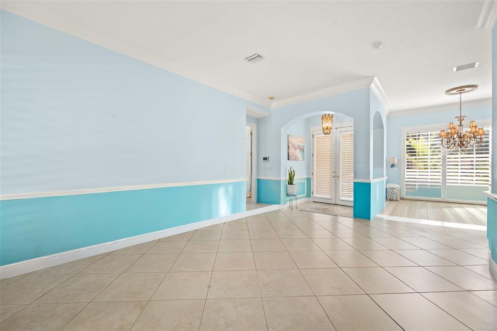 A bright, tiled dining room features two-toned blue walls, an arched entryway, and a chandelier — 6882 TAILFEATHER WAY, BRADENTON, FL