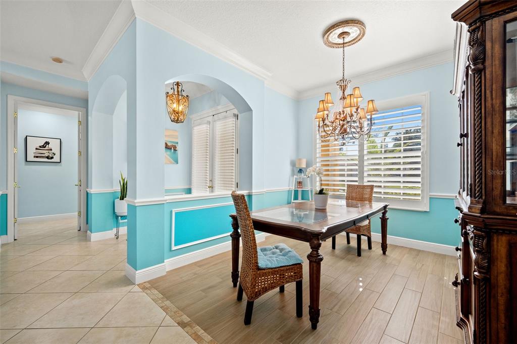 A dining room features light blue walls with wainscoting, a chandelier, and wood-look tile flooring — 6882 TAILFEATHER WAY, BRADENTON, FL