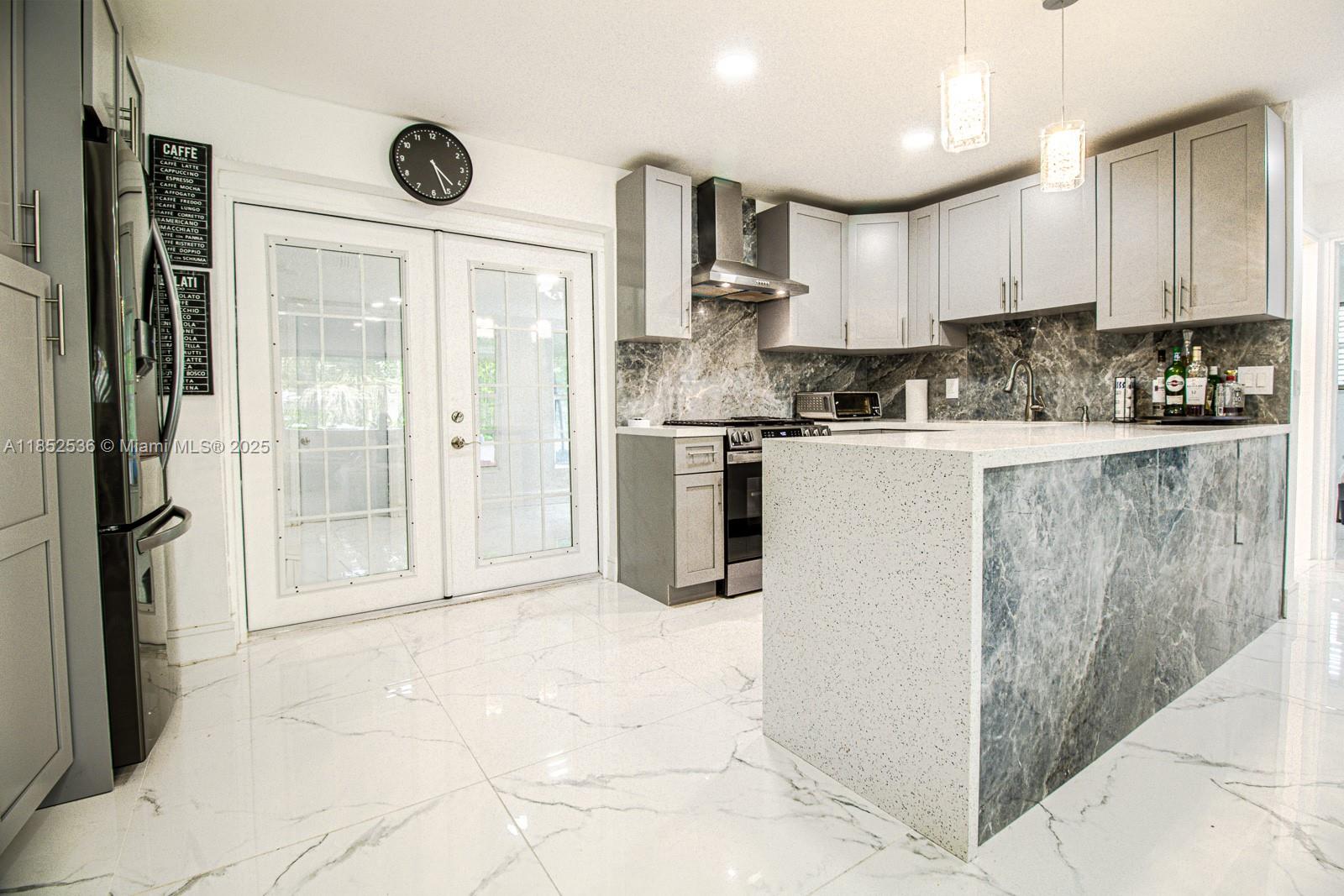 A modern kitchen features gray cabinets, marble-patterned backsplash and island, and white tiled flooring — 5601 SW 38th St, Davie FL 33314, DAVIE, FL