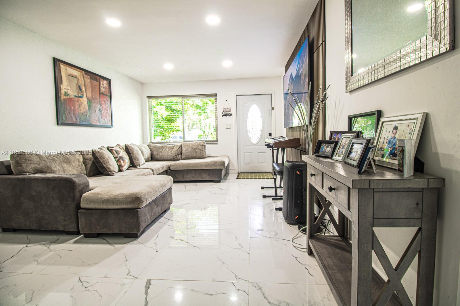 A living room features a large sectional sofa, white marble-style tile floors, and a console table — 5601 SW 38th St, Davie FL 33314, DAVIE, FL