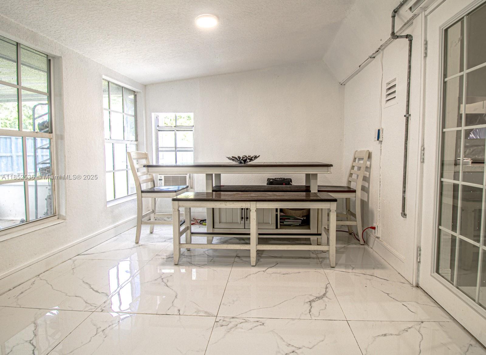 A dining area with white walls, marble-patterned tile floors, and a wooden table set — 5601 SW 38th St, Davie FL 33314, DAVIE, FL