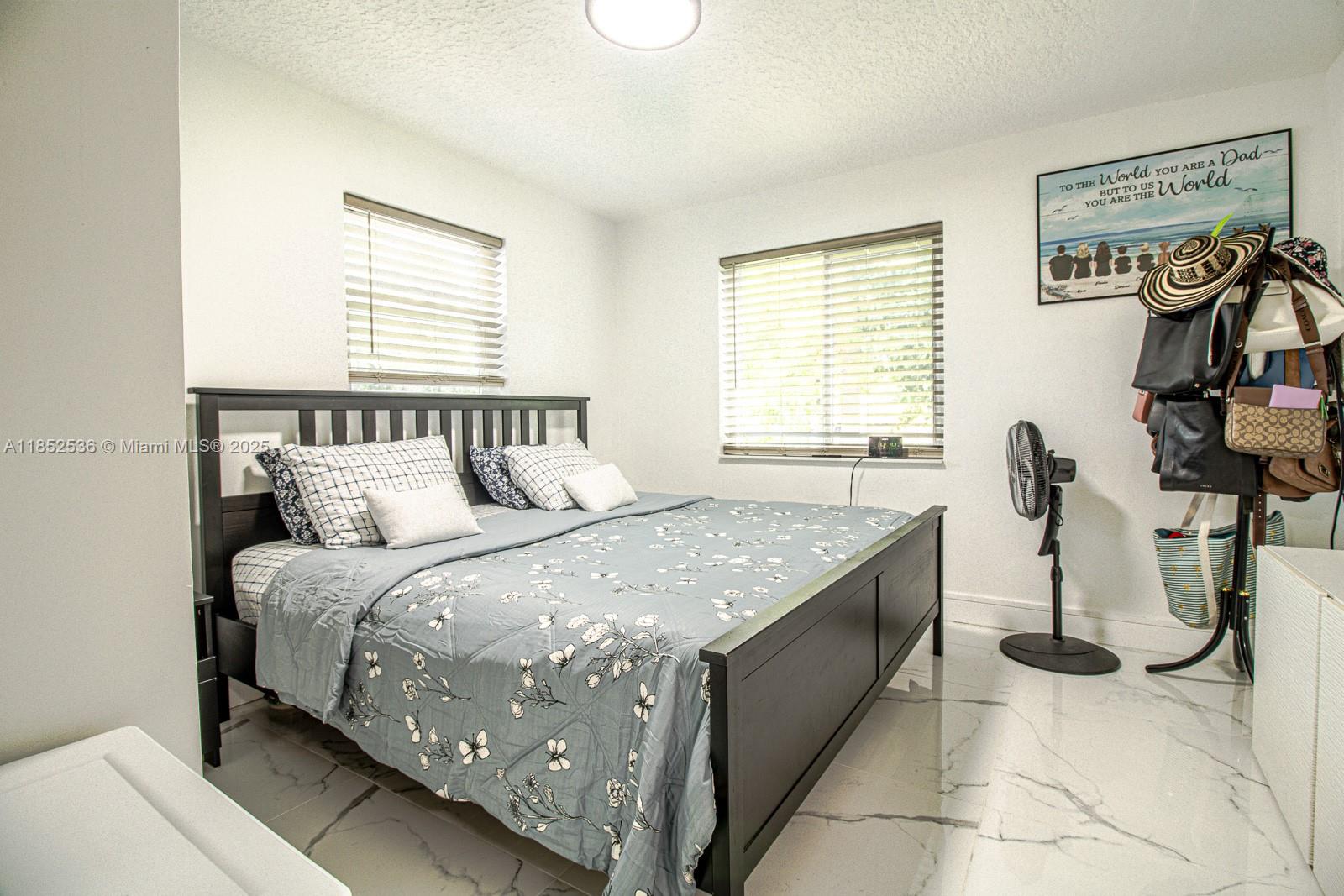 A bedroom features a black bed frame, floral bedding, white walls, and light-colored tiled flooring — 5601 SW 38th St, Davie FL 33314, DAVIE, FL