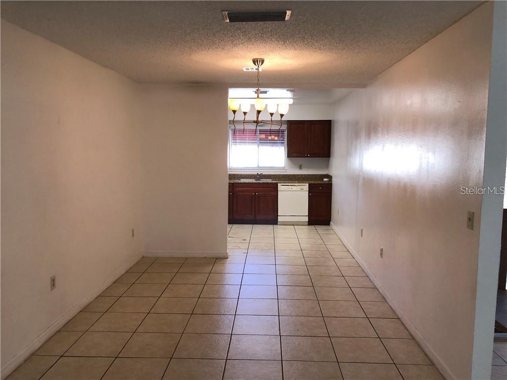 A dining area with tile flooring leads into a kitchen with dark wood cabinets — 4213 S SEMORAN BOULEVARD UNIT 10, ORLANDO, FL
