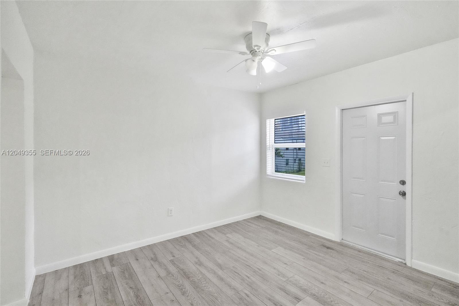 A room with white walls, light wood-look flooring, a ceiling fan, and a white door — 200 NW 13th St # 5, Miami FL 33136, MIAMI, FL