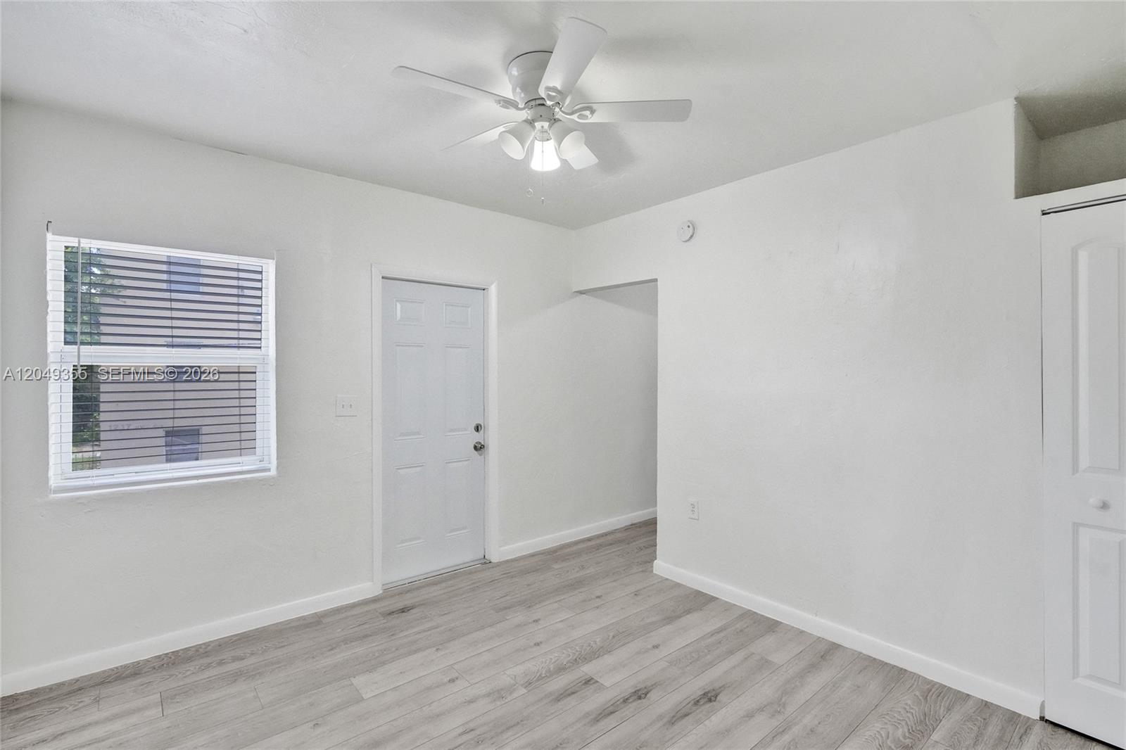 A room with white walls, light wood-look flooring, a ceiling fan, and a white door — 200 NW 13th St # 5, Miami FL 33136, MIAMI, FL