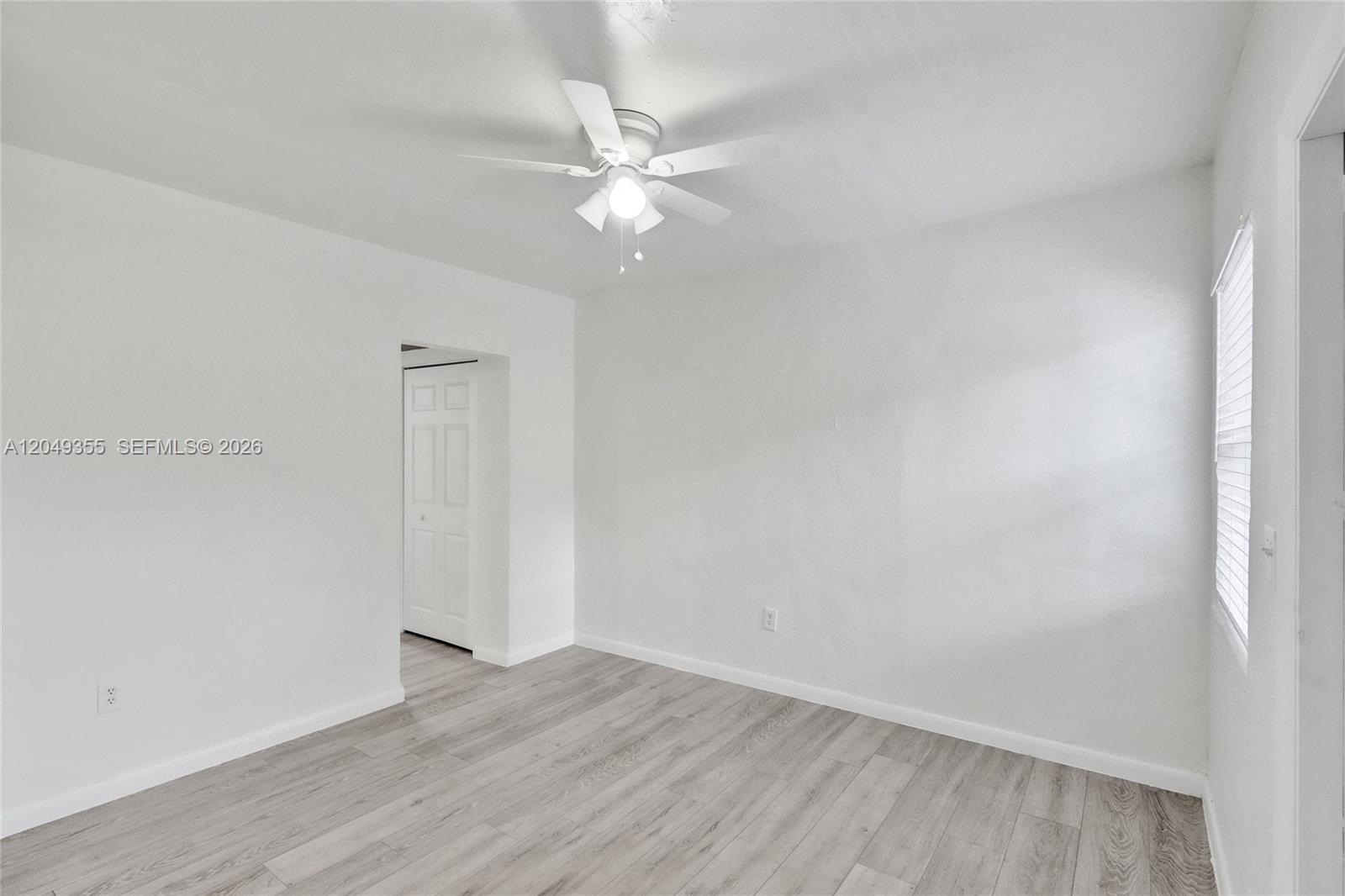 An empty bedroom features white walls, light wood-look flooring, and a ceiling fan — 200 NW 13th St # 5, Miami FL 33136, MIAMI, FL