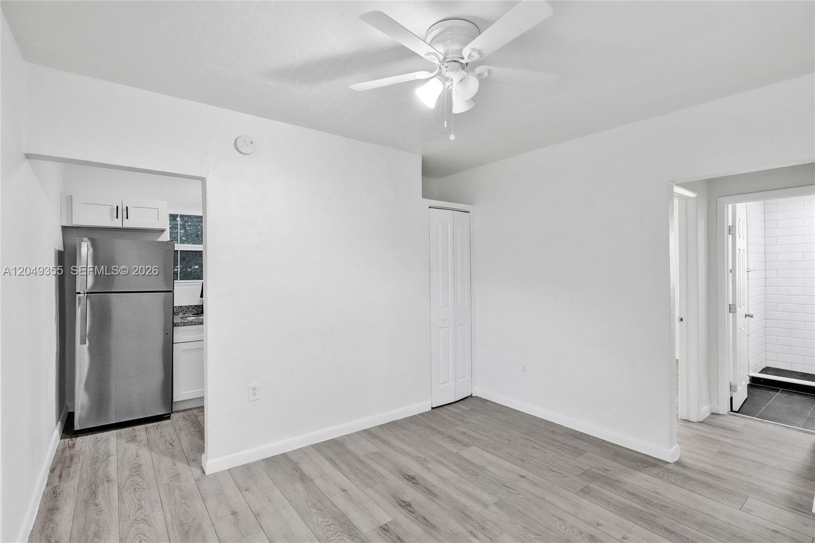 A room with light wood-look flooring, a ceiling fan, a closet, and an adjacent kitchen — 200 NW 13th St # 5, Miami FL 33136, MIAMI, FL
