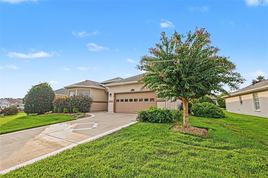 A single-story suburban house with a tan exterior, a two-car garage, and a front lawn — 10888 SE 170TH LANE ROAD, SUMMERFIELD, FL