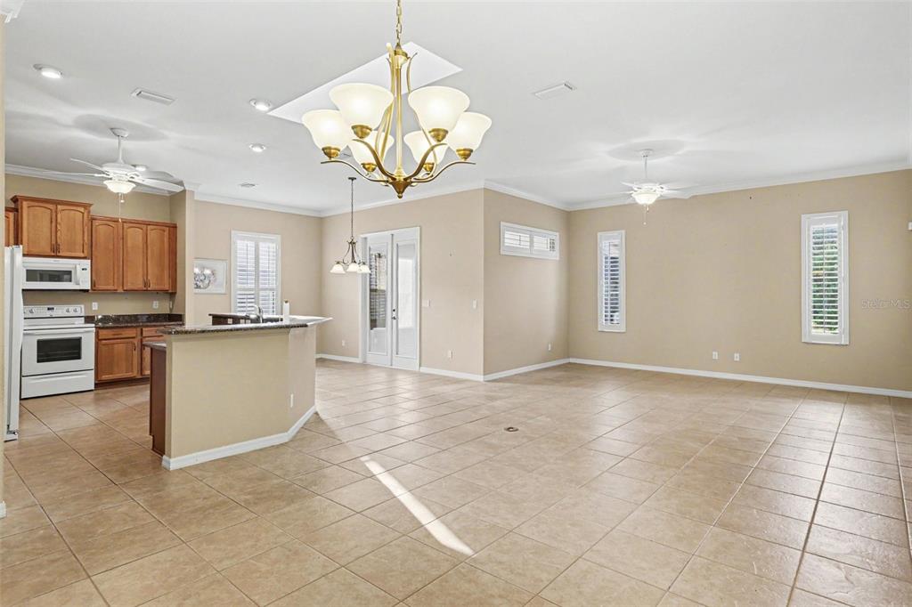 A kitchen with wooden cabinets and a large open living area with tiled floors — 10888 SE 170TH LANE ROAD, SUMMERFIELD, FL