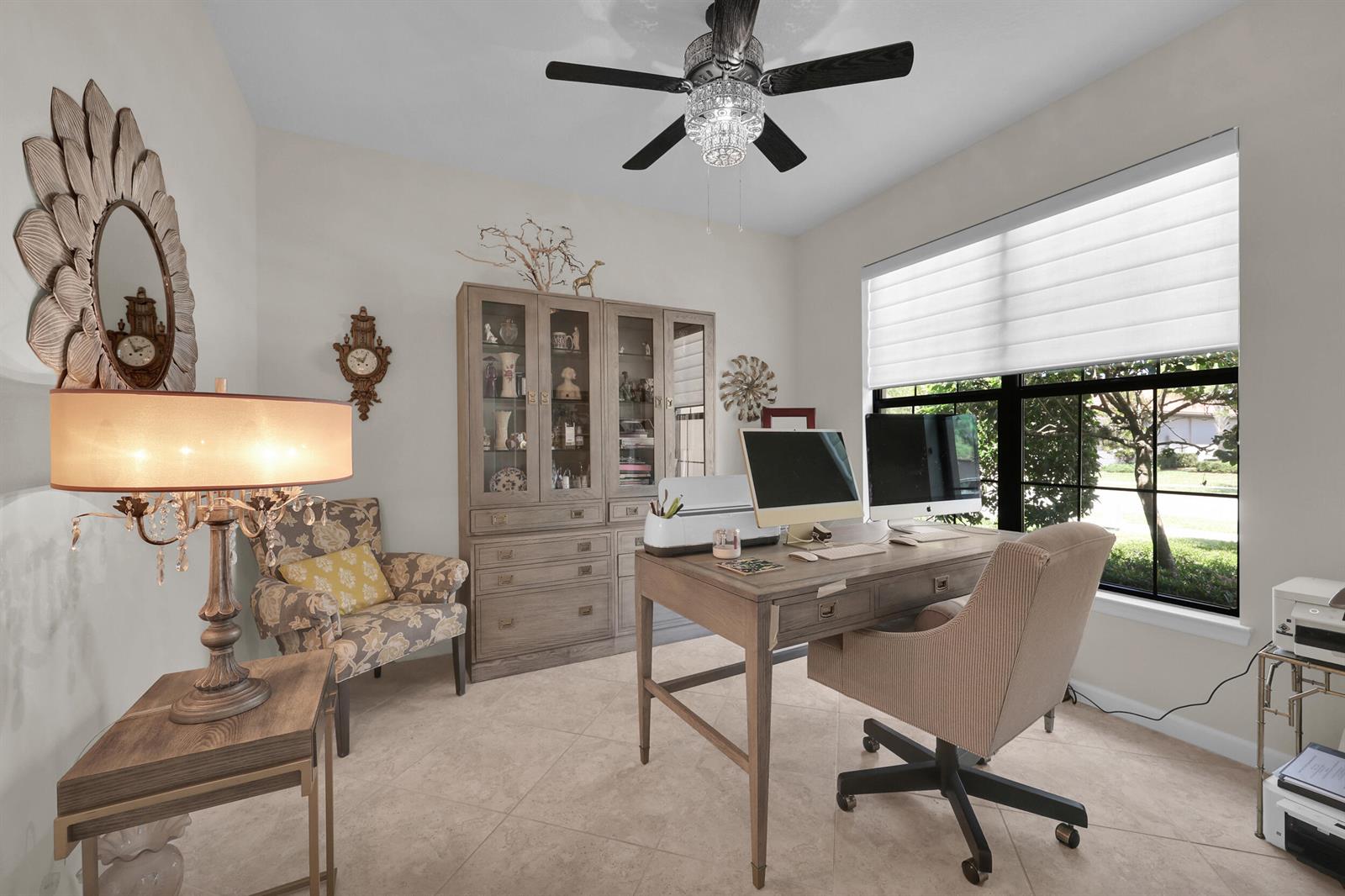 A home office features a wooden desk, a patterned armchair, a display cabinet, and a ceiling fan — 5040 Pendelton Square, Vero Beach FL 32967, VERO BEACH, FL