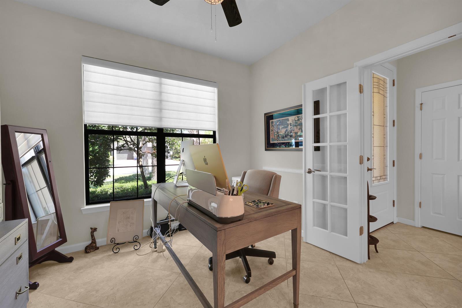 A home office features a wooden desk, a computer, a floor mirror, and tile flooring — 5040 Pendelton Square, Vero Beach FL 32967, VERO BEACH, FL