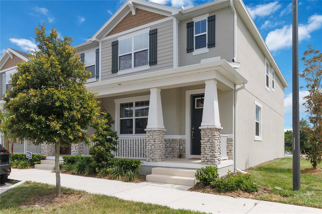 A two-story suburban house with a covered front porch, stone pillars, and light-colored siding — 1326 TARFLOWER DRIVE, WINTER SPRINGS, FL
