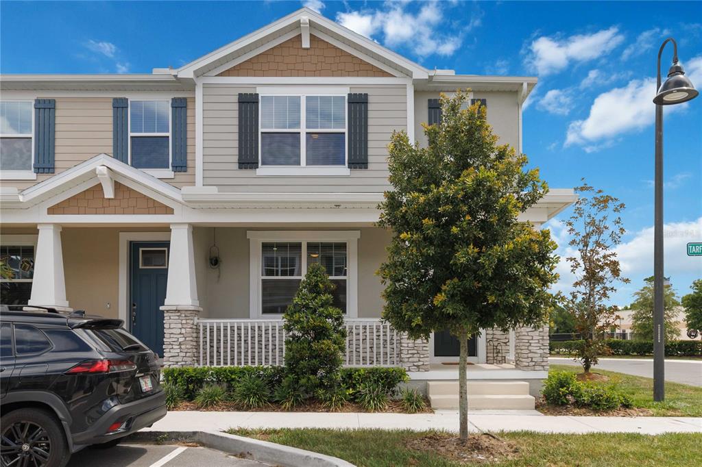 A two-story townhouse with a covered front porch, stone accents, and a parked black SUV — 1326 TARFLOWER DRIVE, WINTER SPRINGS, FL