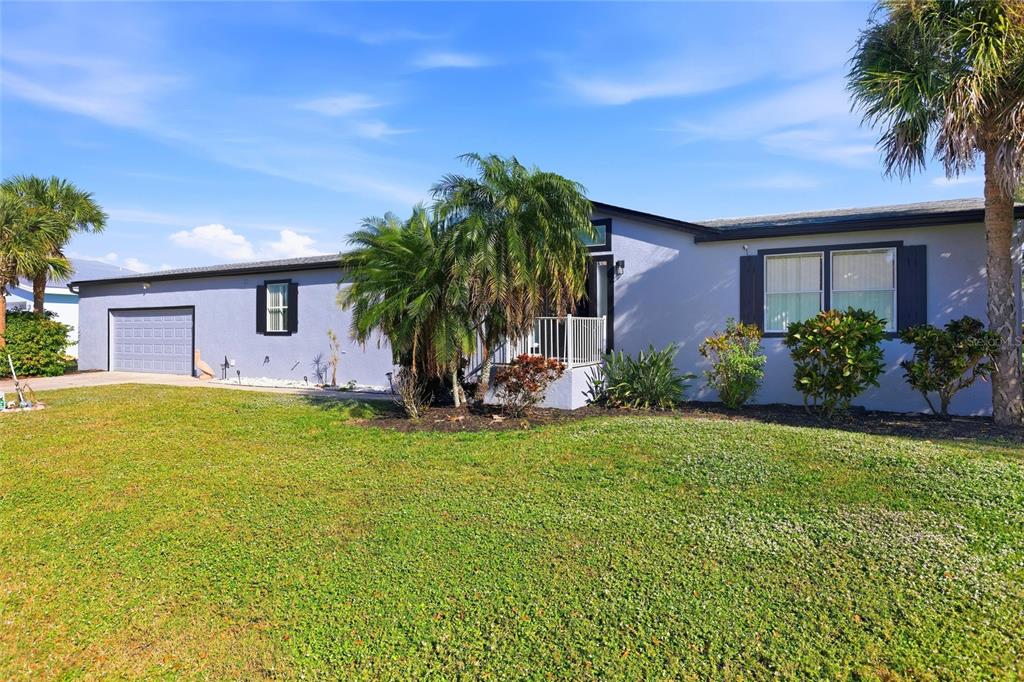 A single-story house with a blue exterior, a garage, and palm trees in the yard — 4190 PELICAN POINTE DRIVE, PUNTA GORDA, FL