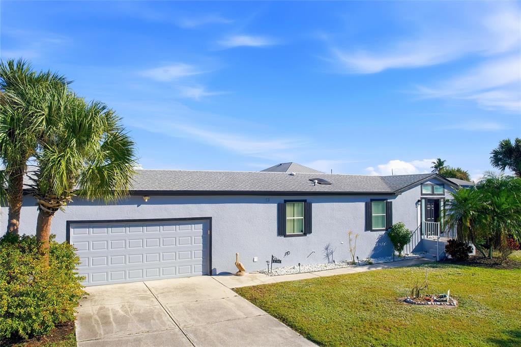 A single-story house with a light blue exterior, a garage, and a palm tree — 4190 PELICAN POINTE DRIVE, PUNTA GORDA, FL