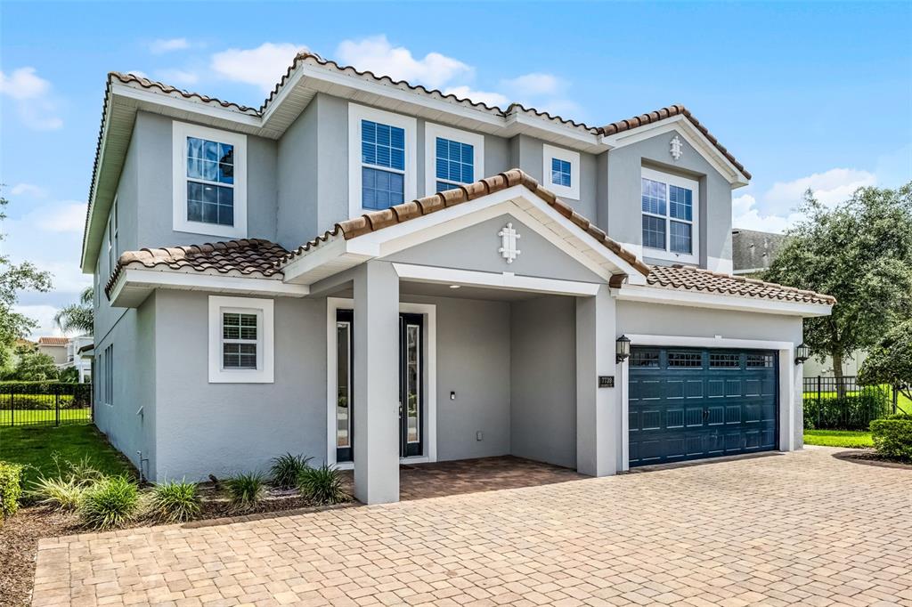 A two-story house with a gray stucco exterior, tile roof, and a paved driveway — 7739 GRABEN STREET, KISSIMMEE, FL