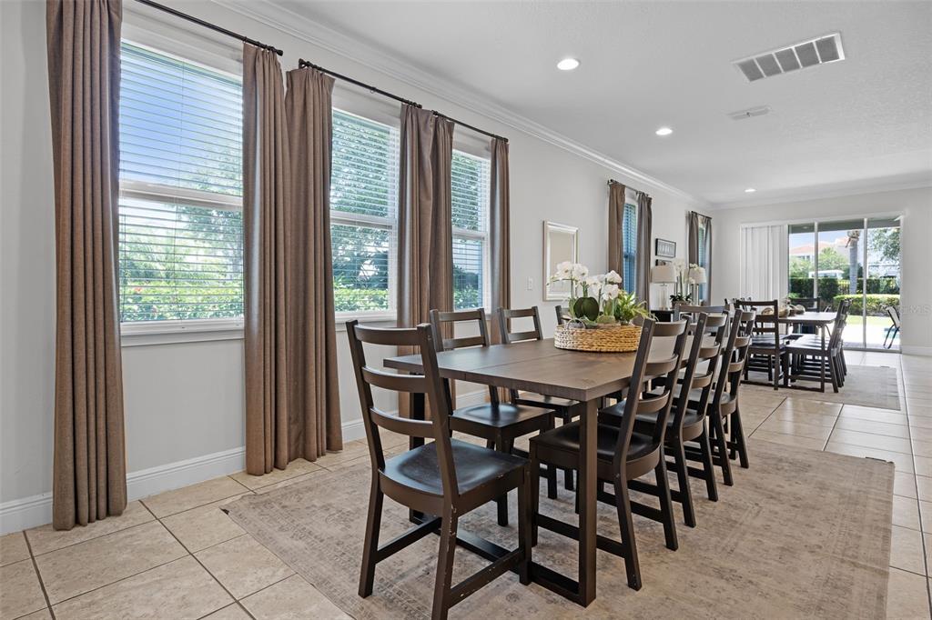 A dining room features a dark wood table with chairs, tile flooring, and large windows — 7739 GRABEN STREET, KISSIMMEE, FL