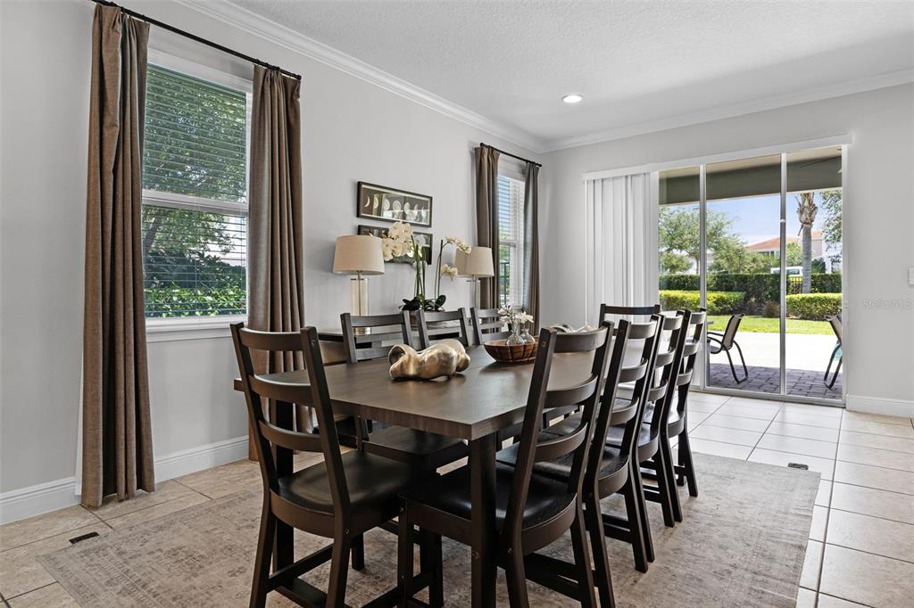 A dining room features a dark wood table and chairs on a neutral area rug — 7739 GRABEN STREET, KISSIMMEE, FL