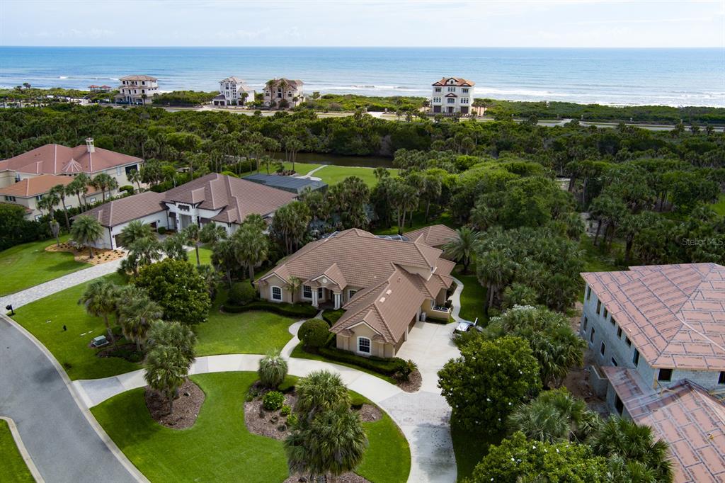 An aerial view shows several large houses near a beach with lush tropical landscaping — 67 ISLAND ESTATES PARKWAY, PALM COAST, FL