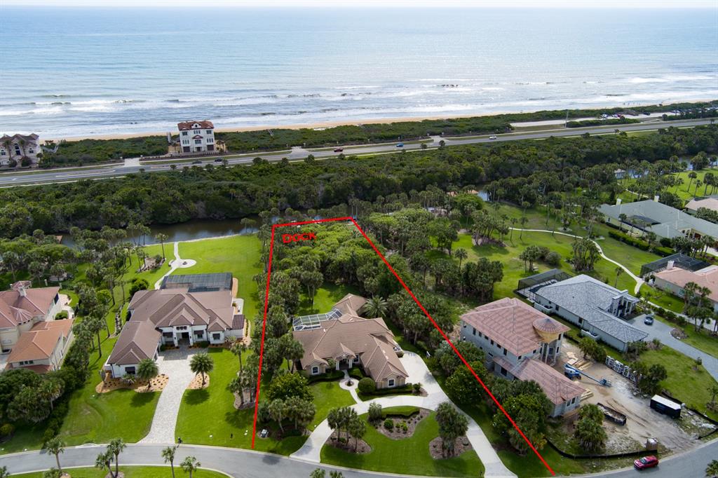 An aerial view shows a residential property with a house, pool, and dock near the ocean — 67 ISLAND ESTATES PARKWAY, PALM COAST, FL