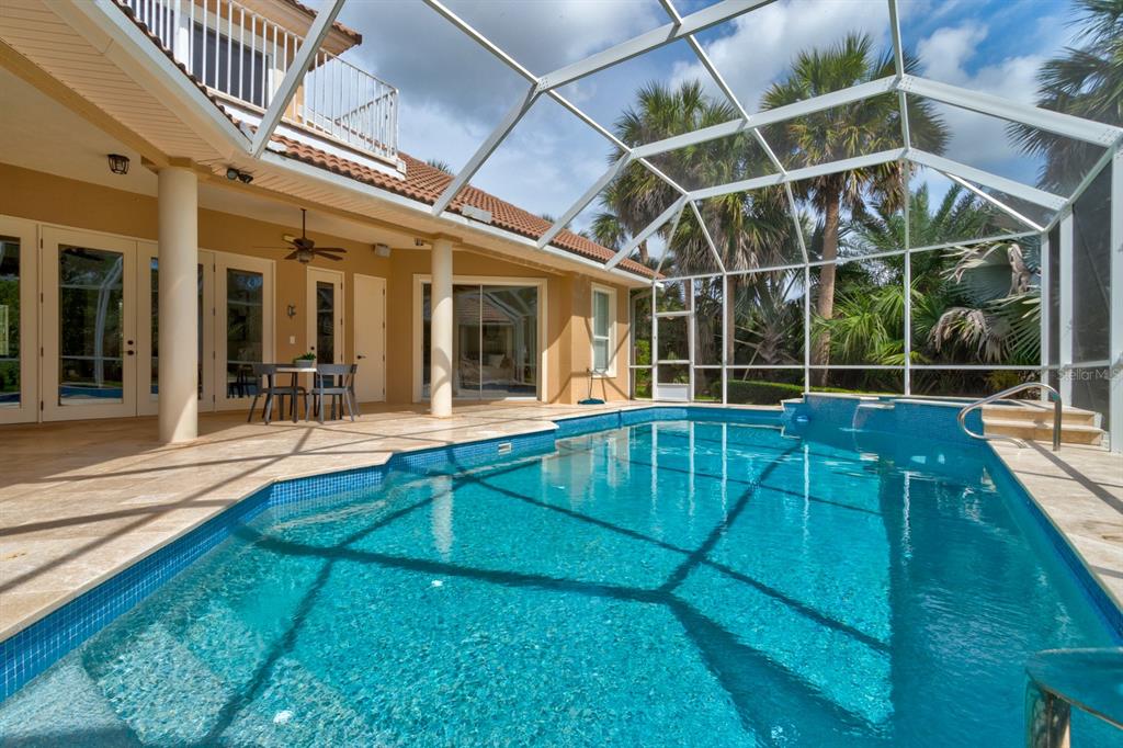 A swimming pool with a screen enclosure sits on a patio next to a house — 67 ISLAND ESTATES PARKWAY, PALM COAST, FL