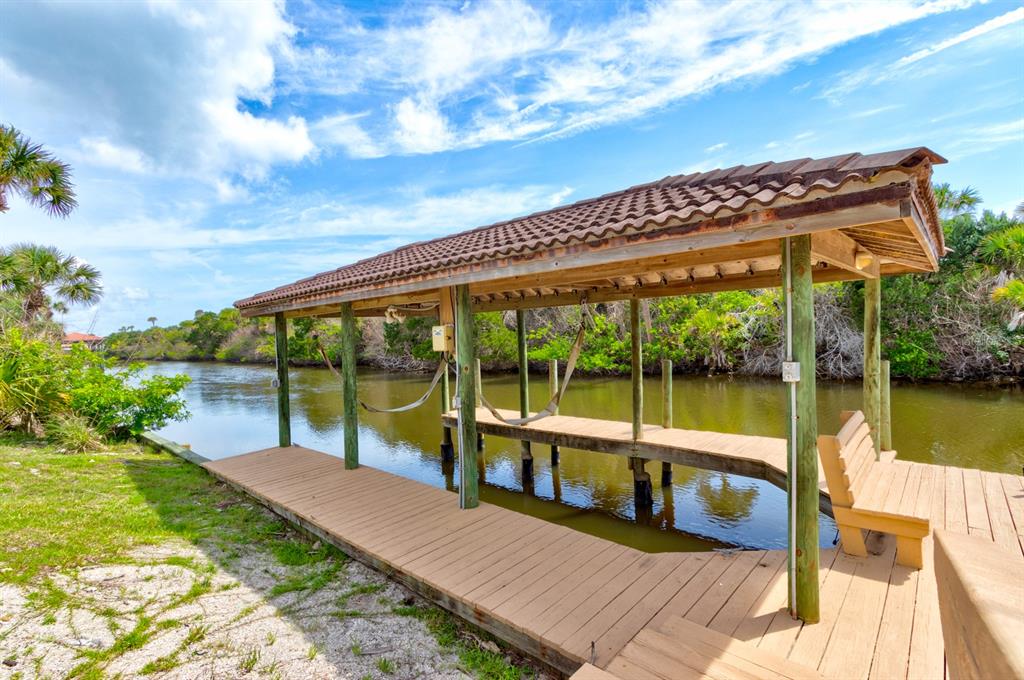 A wooden boat dock with a covered roof sits along a calm canal — 67 ISLAND ESTATES PARKWAY, PALM COAST, FL