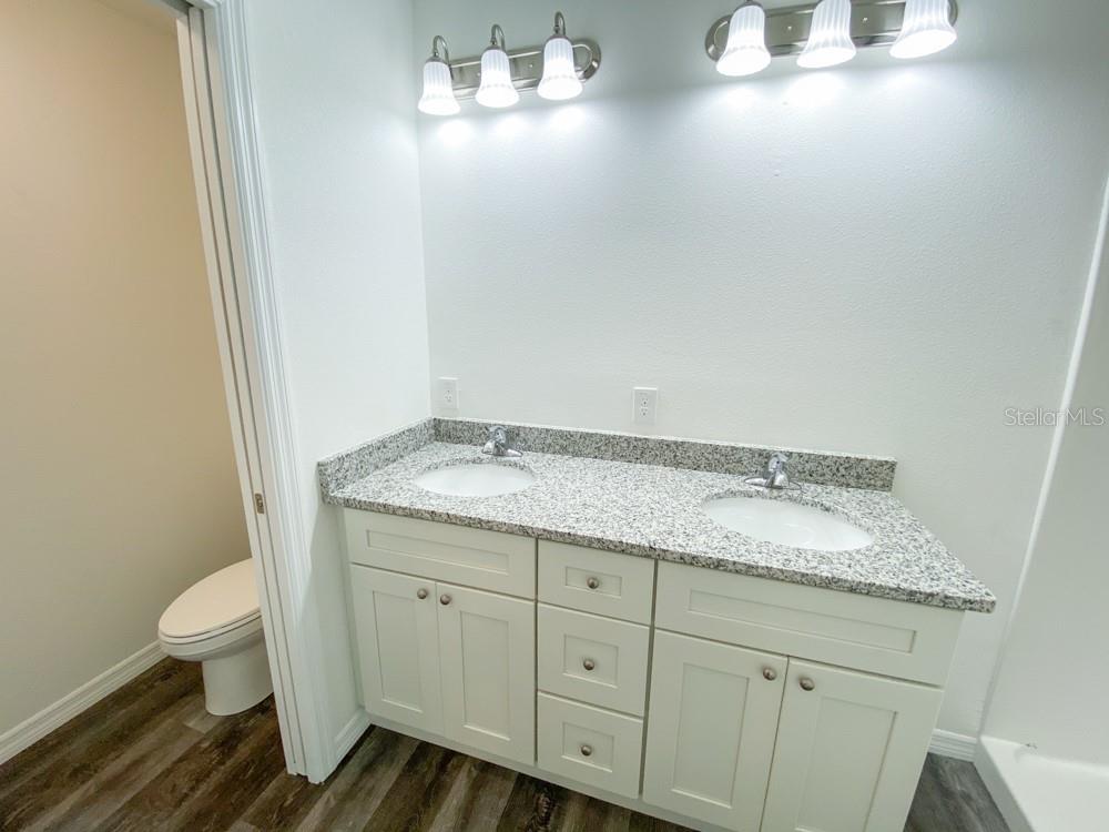 A bathroom features a double-sink vanity with a granite countertop and white cabinetry — 14 LOCUST RADIAL WAY, OCALA, FL