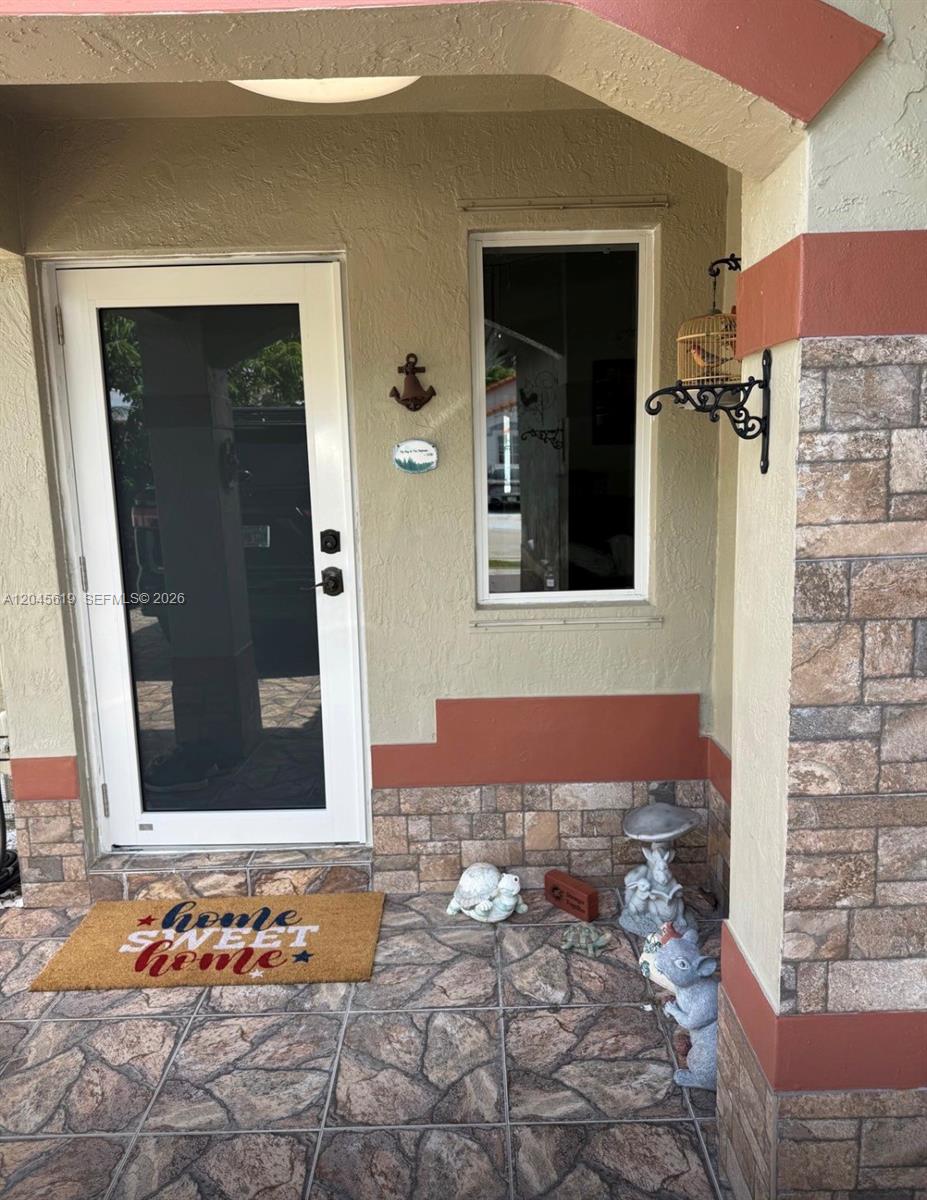 A front porch features a white storm door, a window, and decorative garden statues — 14406 SW 179th Ln, Miami FL 33177, MIAMI, FL