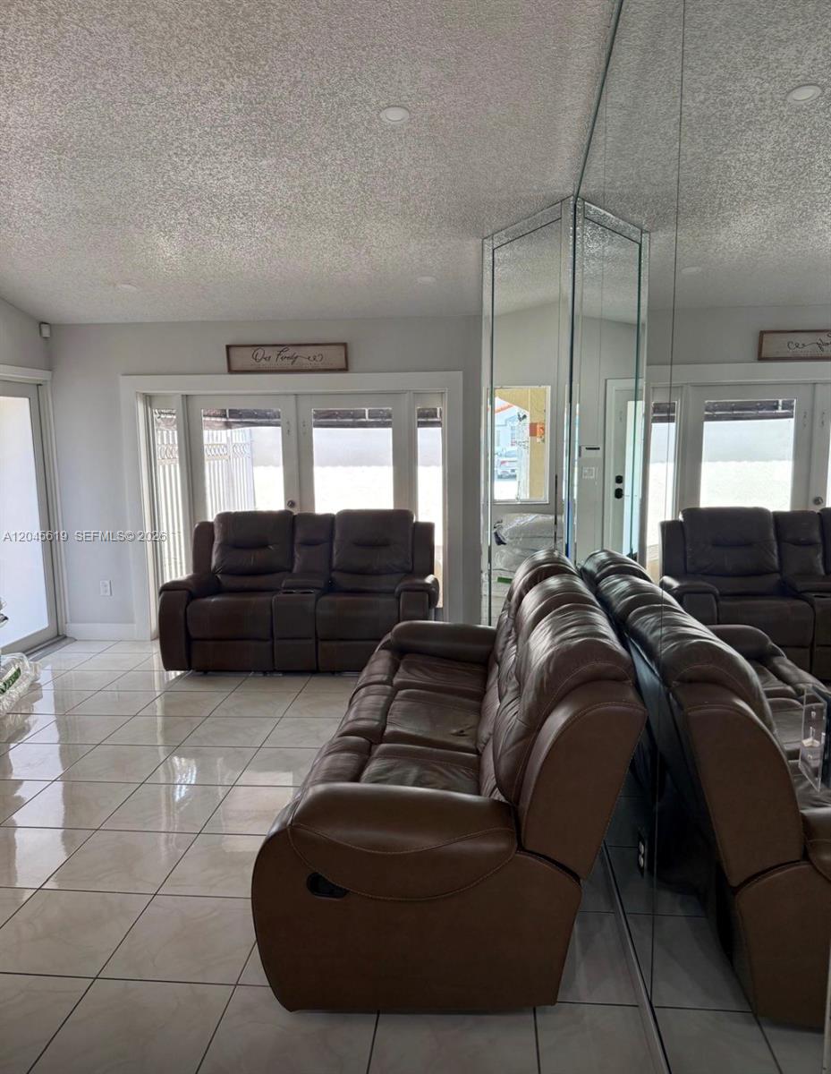 A living room features brown leather reclining sofas, tiled floors, and a large mirrored wall — 14406 SW 179th Ln, Miami FL 33177, MIAMI, FL