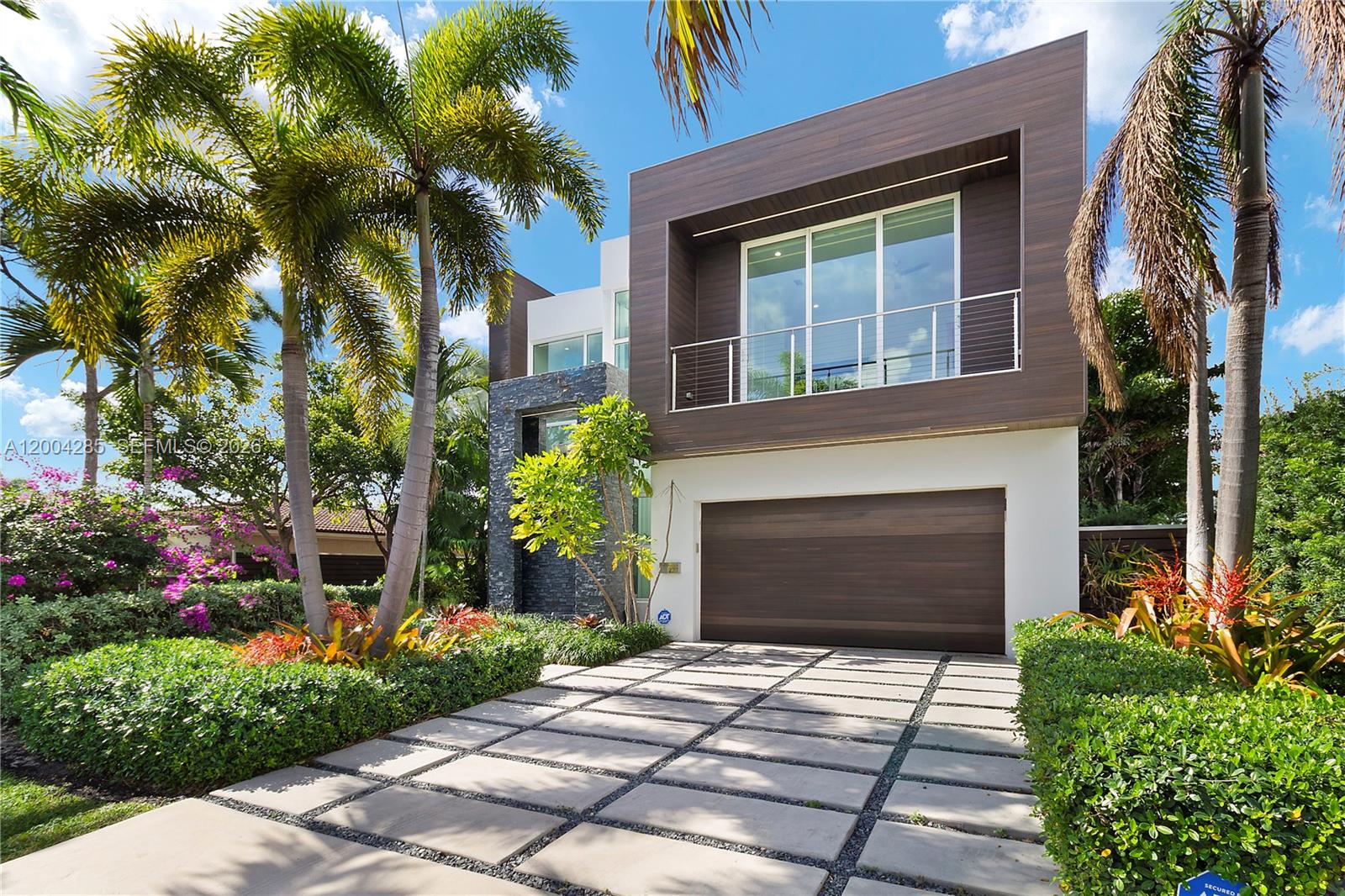 A modern two-story house features a wood-paneled upper level, a garage, and palm trees — 2217 NE 17th Ter, Wilton Manors FL 33305, WILTON MANORS, FL