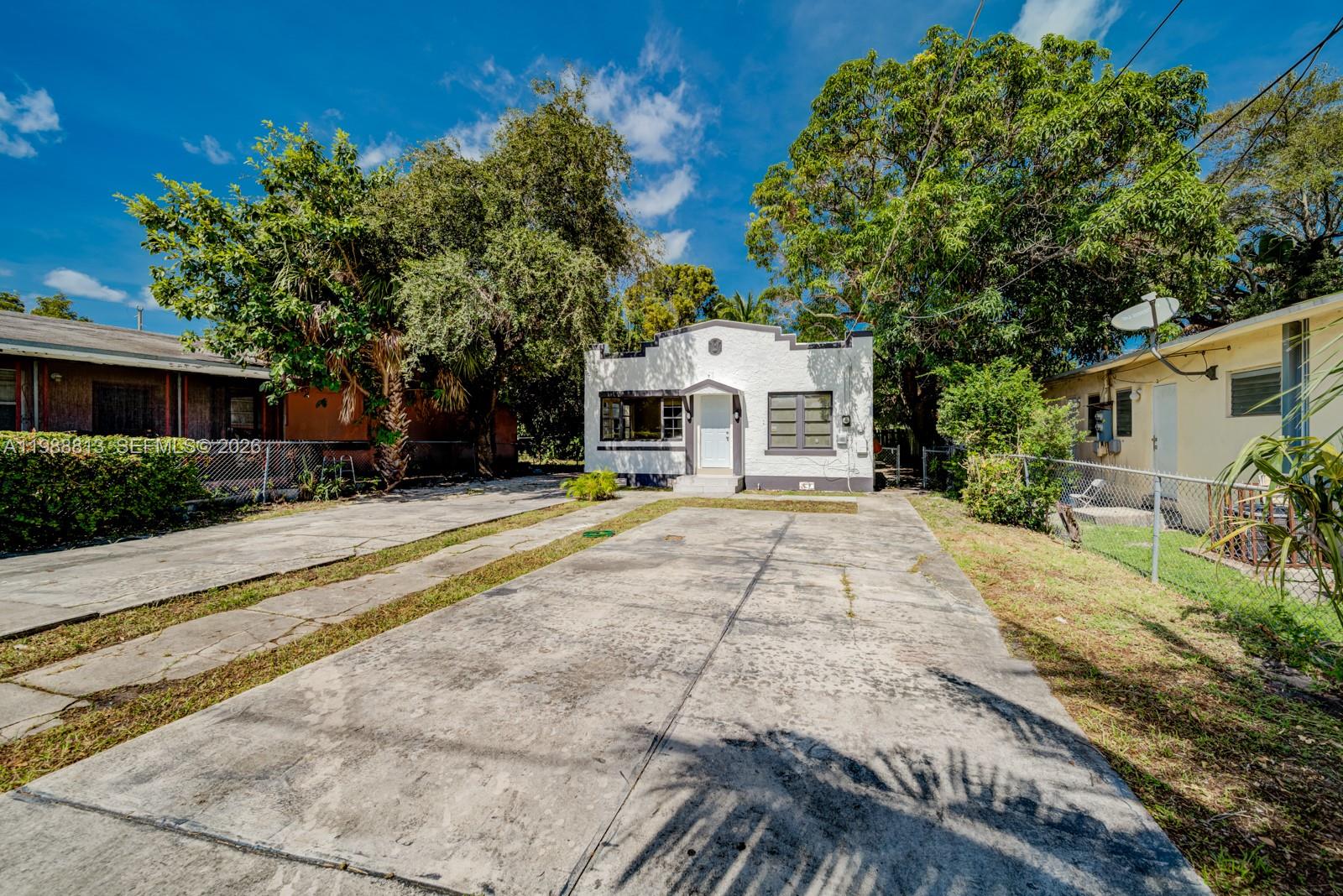 A white, single-story house with a flat roof and a concrete driveway in front — 829 NW 56th St, Miami FL 33127, MIAMI, FL