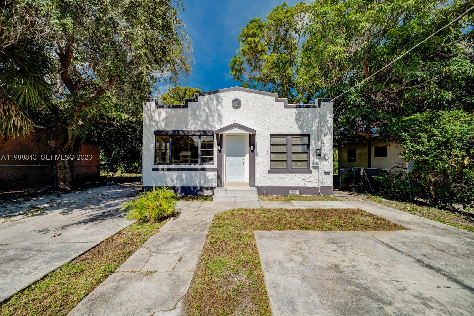 A white, single-story house with a stepped parapet roof and a concrete driveway — 829 NW 56th St, Miami FL 33127, MIAMI, FL