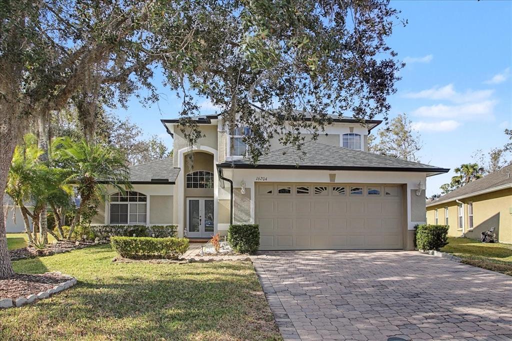 A living room with high ceilings, a staircase, tile flooring, and a leather sectional sofa — 16204 HAMPTON TRACE COURT, TAMPA, FL