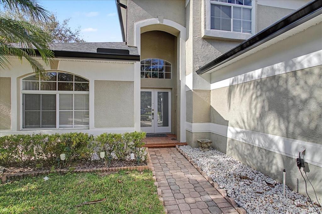 A tiled entryway features double frosted glass doors, a glass console table, and a wall mirror — 16204 HAMPTON TRACE COURT, TAMPA, FL