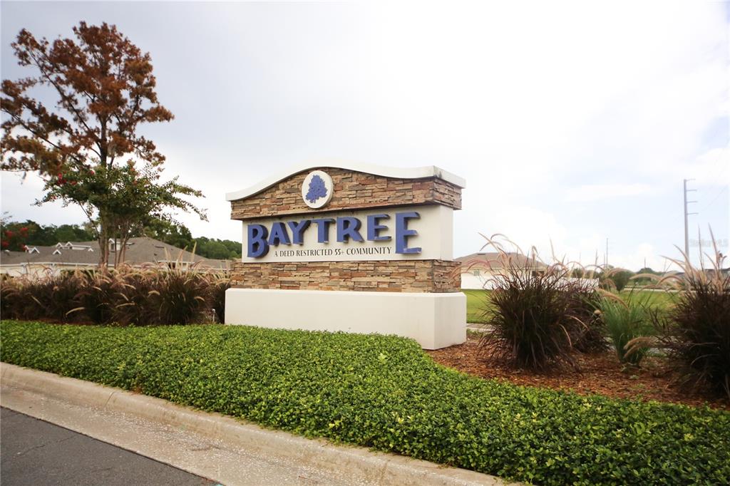 A stone monument sign for the Baytree 55+ community stands in a landscaped yard — 136 BAYTREE BOULEVARD, TAVARES, FL