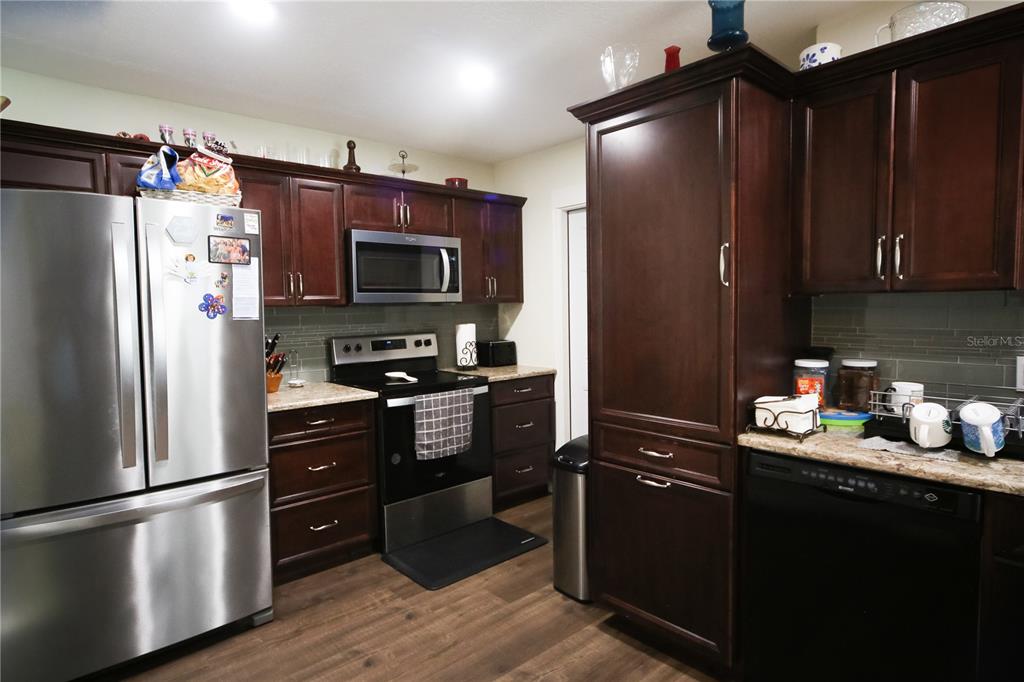 A kitchen features dark wood cabinets, stainless steel appliances, and a light-colored countertop — 136 BAYTREE BOULEVARD, TAVARES, FL