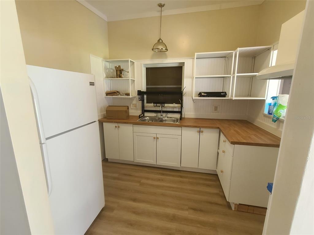 A kitchen features white cabinets, open shelving, a wood countertop, and a white refrigerator — 6260 LANDOVER TERRACE, NORTH PORT, FL