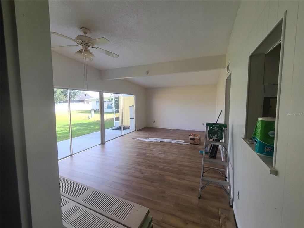 An interior view of a room with wood-look flooring, a ceiling fan, and sliding glass doors — 6260 LANDOVER TERRACE, NORTH PORT, FL
