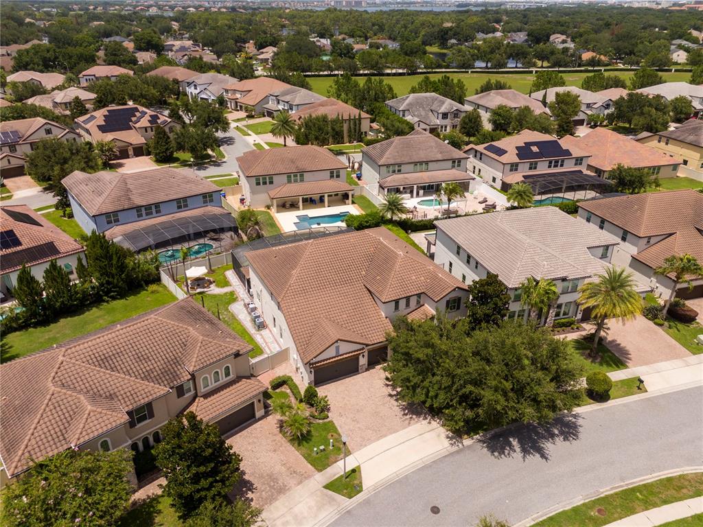 An aerial view shows several suburban houses with tiled roofs, swimming pools, and paved driveways — 8457 MOREHOUSE DRIVE, ORLANDO, FL