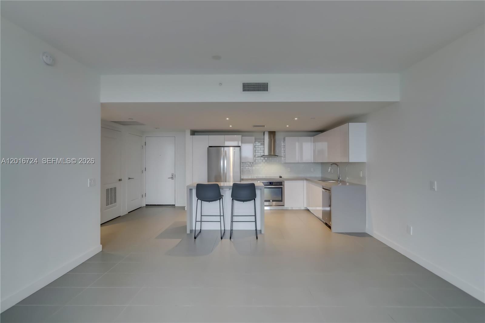 A modern kitchen features white cabinets, stainless steel appliances, and a central island with stools — 1600 NE 1st Ave # 1918, Miami FL 33132, MIAMI, FL