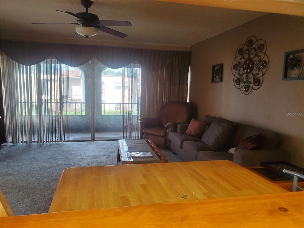 A living room features a sofa, armchair, coffee table, and sliding glass doors to a balcony — 7701 STARKEY ROAD UNIT 316, SEMINOLE, FL