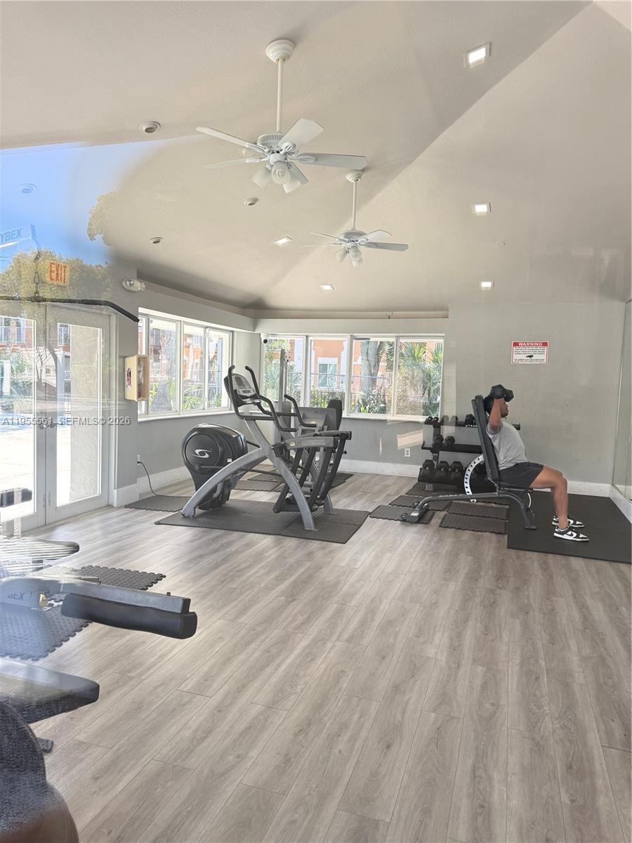 A gym features light wood-look flooring, ceiling fans, large windows, and exercise equipment — 7120 NW 179th St # 105, Hialeah FL 33015, HIALEAH, FL
