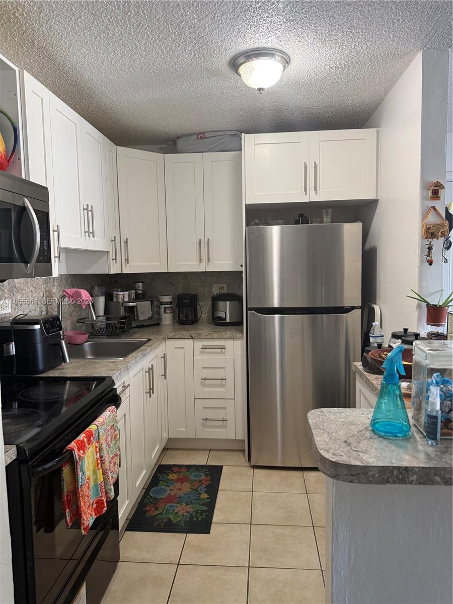A kitchen features white cabinets, stainless steel appliances, and light-colored countertops — 7120 NW 179th St # 105, Hialeah FL 33015, HIALEAH, FL