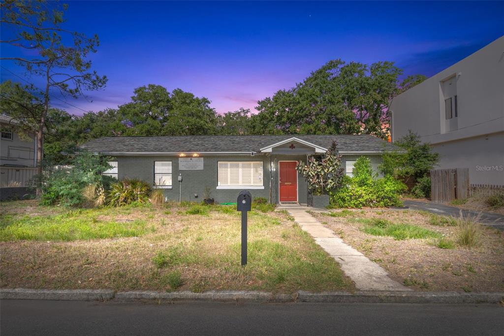 A single-story gray brick house with a red front door and a front lawn — 110 N LINCOLN AVENUE, TAMPA, FL