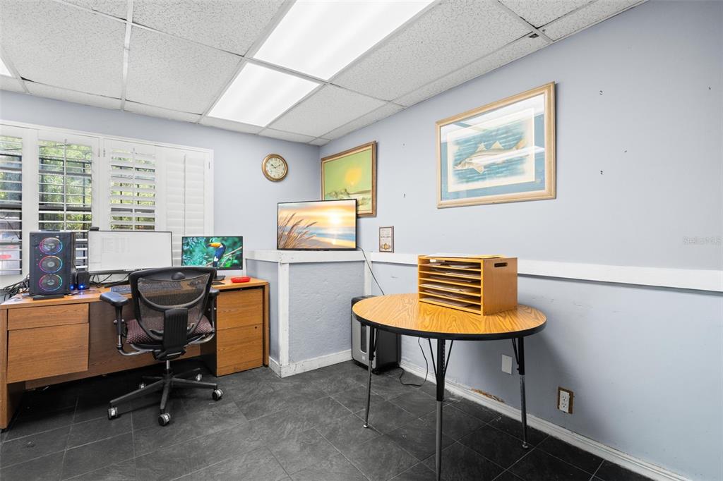 A home office features a wooden desk, a round table, and two framed wall pictures — 110 N LINCOLN AVENUE, TAMPA, FL