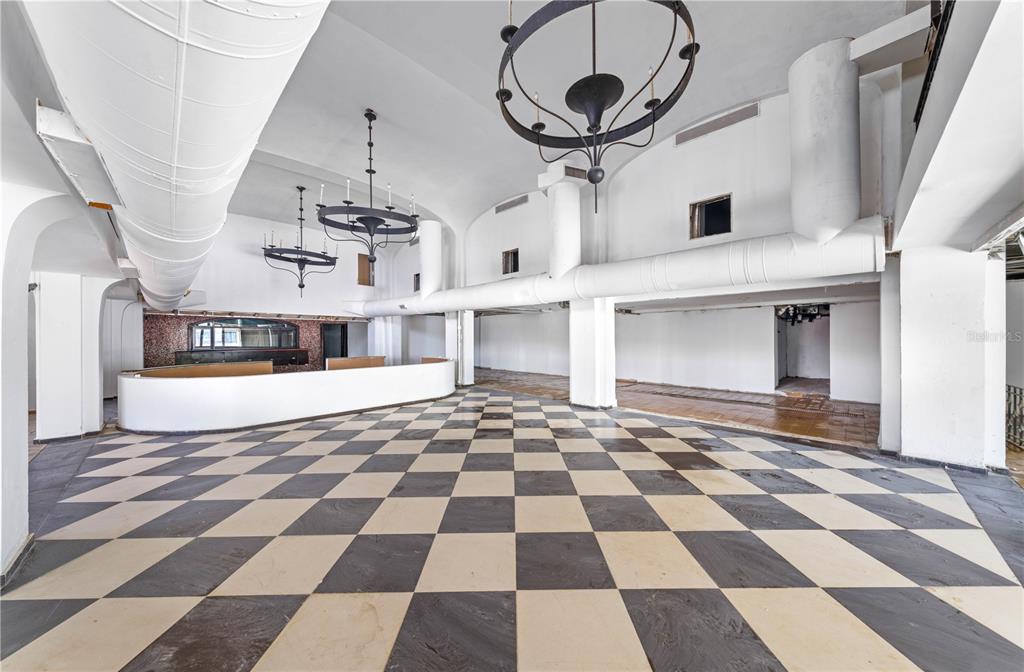 A large, empty room features a black-and-white checkered floor, white walls, and two hanging chandeliers — 201-202 TIZOL STREET, SAN JUAN, PR