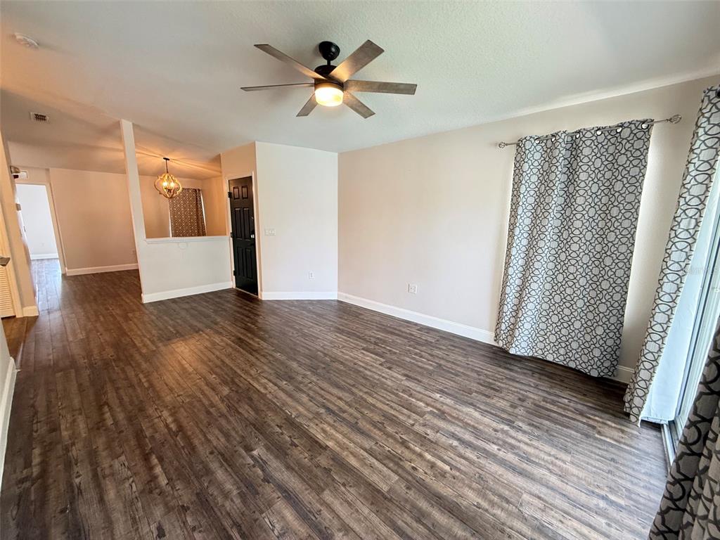 A living room features wood-look flooring, a ceiling fan, and a black front door — 8846 GRAND PALMS CIRCLE UNIT B, KISSIMMEE, FL