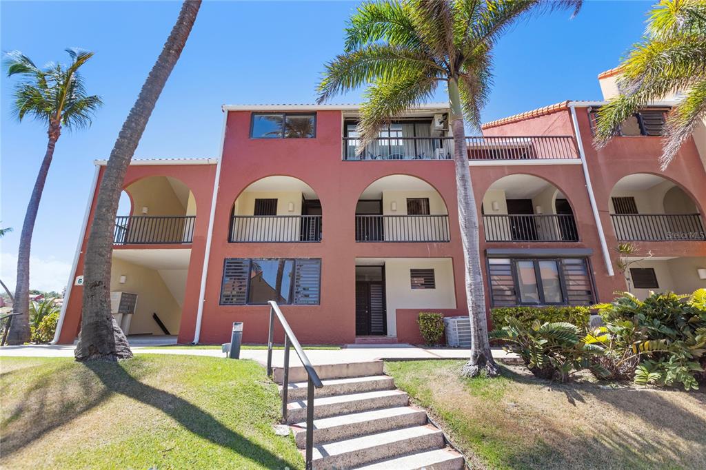 A three-story, terracotta-colored apartment building features arched balconies and a central staircase — . BEACH VILLAGE UNIT 128, HUMACAO, PR