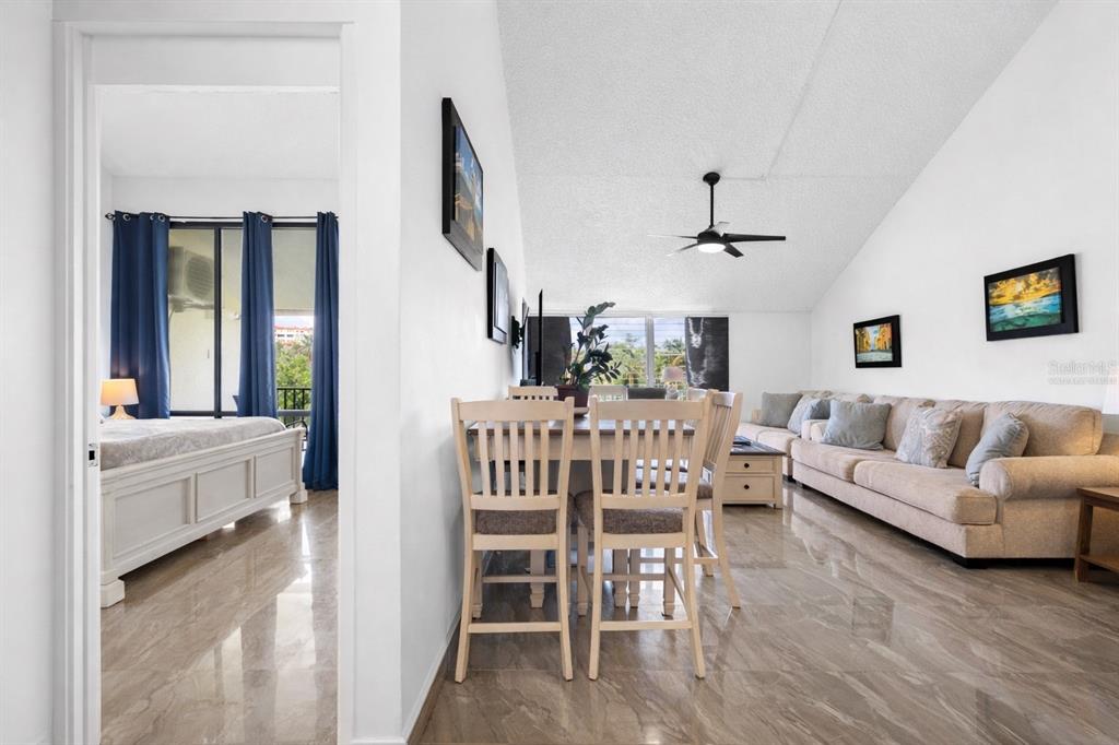 A living room and dining area with tile floors, a vaulted ceiling, and a bedroom view — . BEACH VILLAGE UNIT 128, HUMACAO, PR
