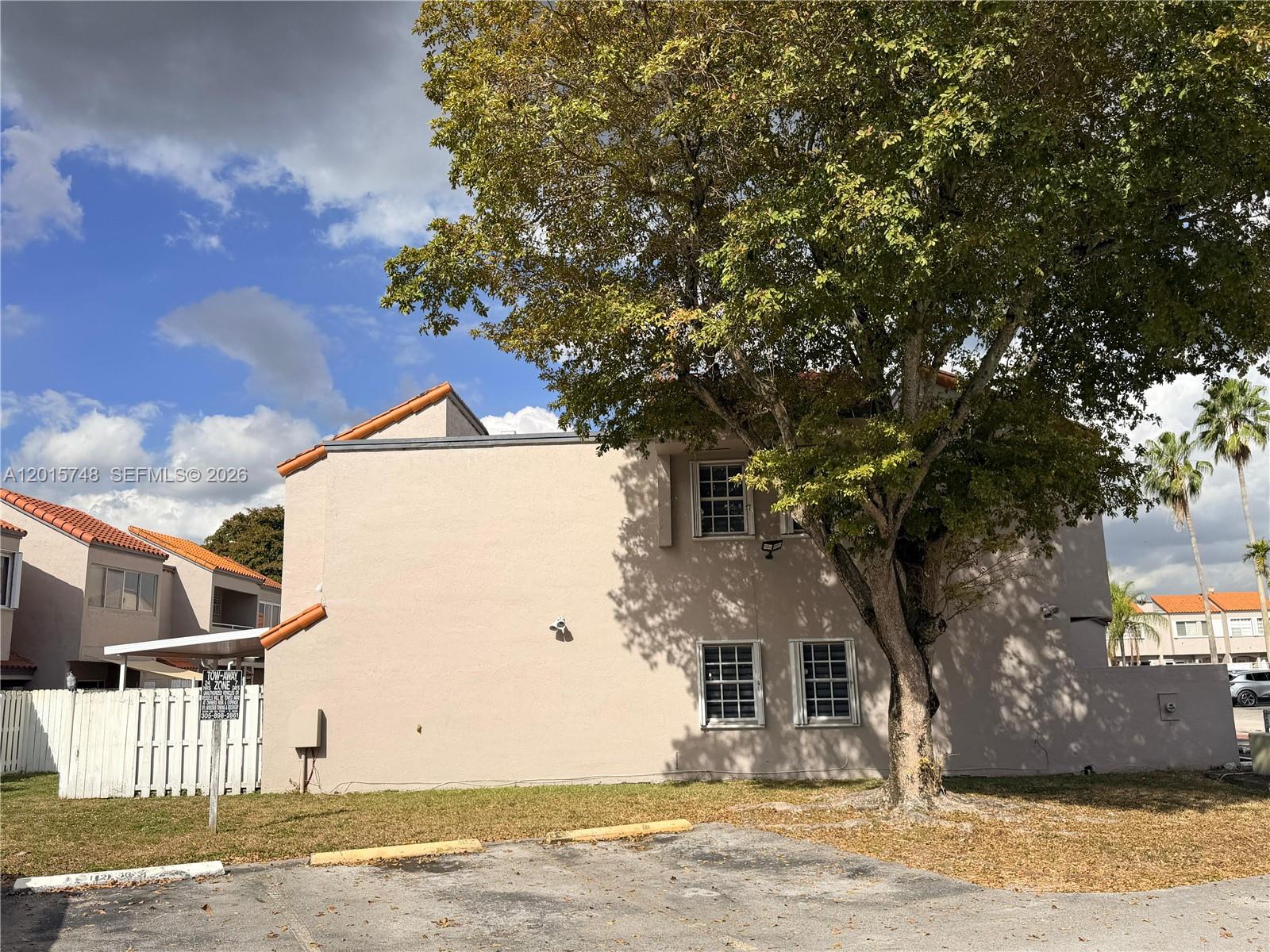 A two-story tan building with a large tree stands beside a white fence — 6514 SW 128th Pl # 6514, Miami FL 33183, MIAMI, FL